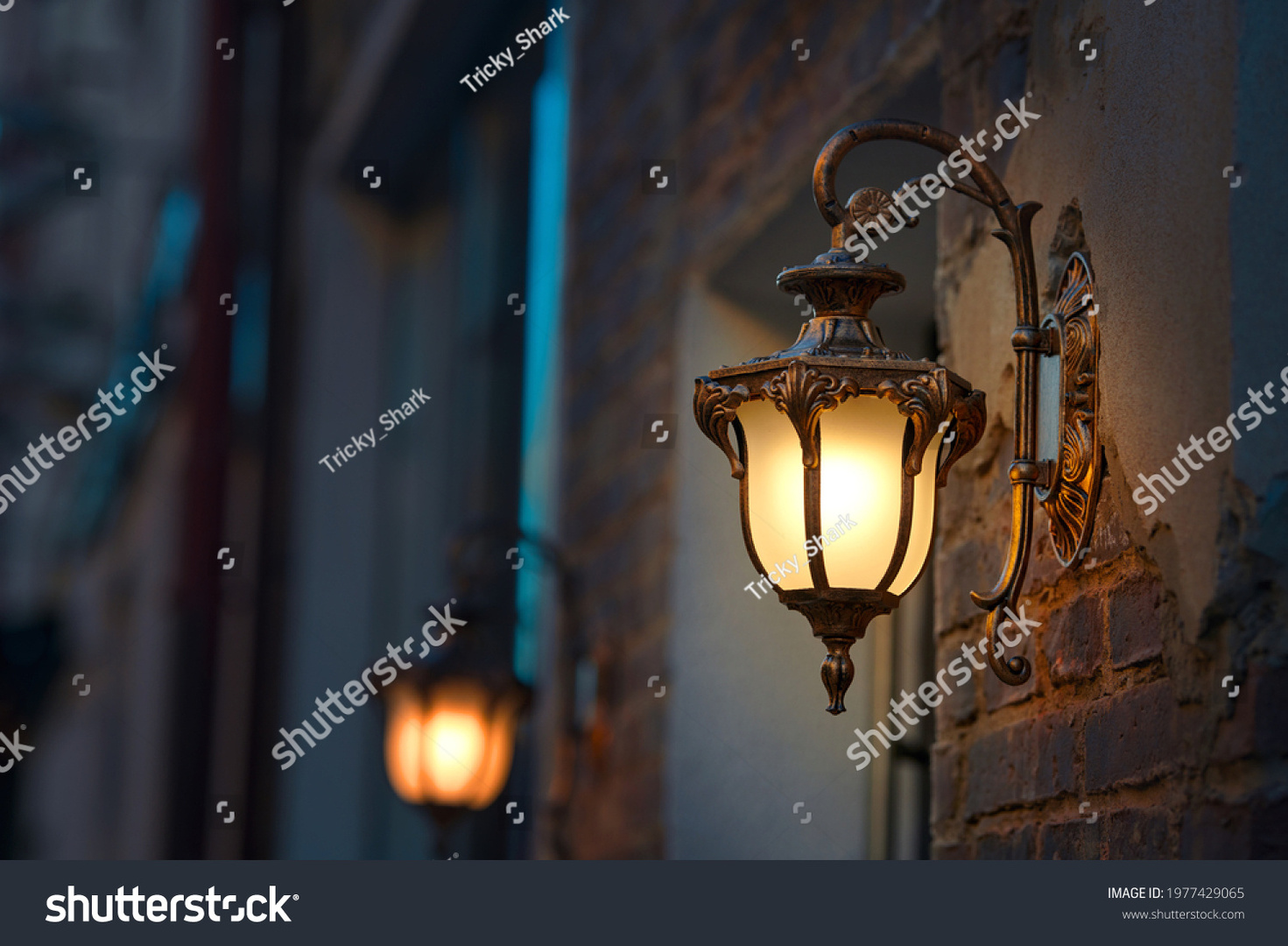 stock-photo-lantern-with-yellow-warm-light-on-facade-of-building-twilight-on-city-street-building-1977429065.jpg